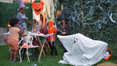 Group of multi-ethnic kids in Halloween costumes celebrating together in a decorated backyard