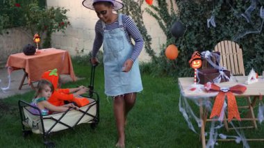 Children in costumes playing together in a decorated backyard on Halloween