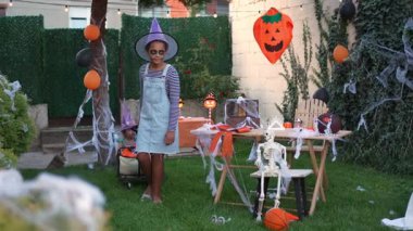 Young girl pulling a wagon with kids in costumes during a Halloween party in a decorated garden