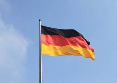 Mavi gökyüzü arka planında rüzgarda sallanan Alman bayrağı 