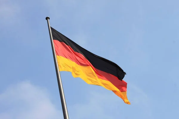 German flag waving on wind on blue sky background