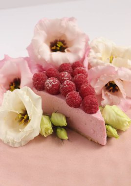 Ahudududulu cheesecake, taze çiçekli fotoğraf, pembe kek, beyaz arka plan konsept yiyecek sanatı tabağında böğürtlenli pasta.