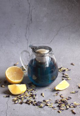 Gri arka planda kuru çay yaprakları olan çaydanlığın yakın çekimi 