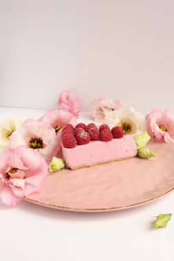 Ahudududulu cheesecake, taze çiçekli fotoğraf, pembe kek, beyaz arka plan konsept yiyecek sanatı tabağında böğürtlenli pasta.