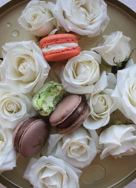 Macaroons and white roses, fashion flat lay photo with cookies and flowers on golden plate