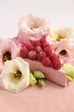 Ahudududulu cheesecake, taze çiçekli fotoğraf, pembe kek, beyaz arka plan konsept yiyecek sanatı tabağında böğürtlenli pasta.