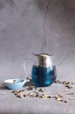 Gri arka planda kuru çay yaprakları olan çaydanlığın yakın çekimi 