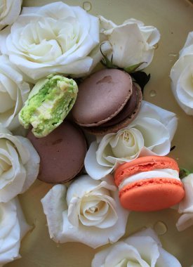 Makarnalar ve beyaz güller, düz moda fotoğraf, kurabiyeler ve altın tepside çiçekler.