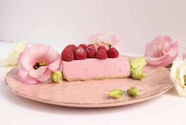 Ahudududulu cheesecake, taze çiçekli fotoğraf, pembe kek, beyaz arka plan konsept yiyecek sanatı tabağında böğürtlenli pasta.