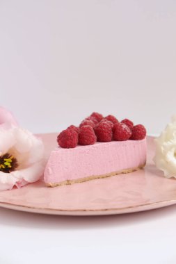 Ahudududulu cheesecake, taze çiçekli fotoğraf, pembe kek, beyaz arka plan konsept yiyecek sanatı tabağında böğürtlenli pasta.