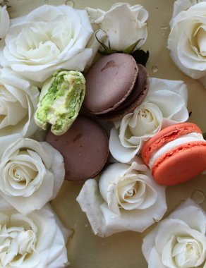 Makarnalar ve beyaz güller, düz moda fotoğraf, kurabiyeler ve altın tepside çiçekler.