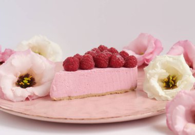 Ahudududulu cheesecake, taze çiçekli fotoğraf, pembe kek, beyaz arka plan konsept yiyecek sanatı tabağında böğürtlenli pasta.