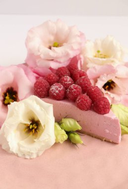 Ahudududulu cheesecake, taze çiçekli fotoğraf, pembe kek, beyaz arka plan konsept yiyecek sanatı tabağında böğürtlenli pasta.