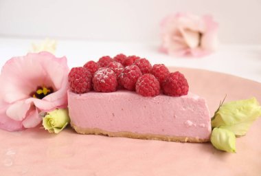 Ahudududulu cheesecake, taze çiçekli fotoğraf, pembe kek, beyaz arka plan konsept yiyecek sanatı tabağında böğürtlenli pasta.