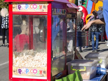 A young man sells popcorn and cotton candy in the square. clipart