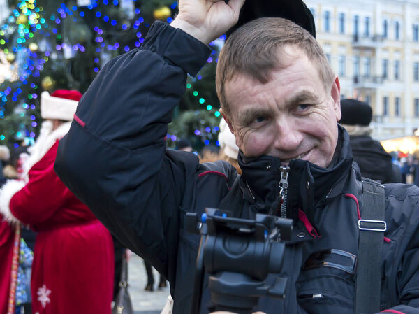 A man, videographer, is preparing to shoot a holiday on New Year's Square. In his hands monopod.