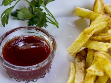 Beyaz renk, kızarmış patates kızartması, sosu, yeşil fışkın maydanoz bir plaka üzerinde.