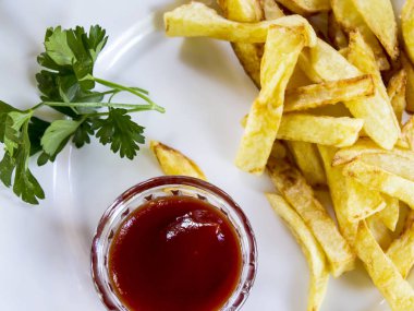 Beyaz renk, kızarmış patates kızartması, sosu, yeşil fışkın maydanoz bir plaka üzerinde.