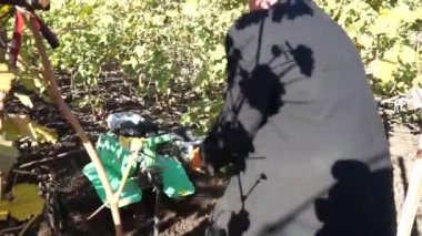 Bir erkekte bir mini Kültüvatör ile yere kazma iş elbiseleri.