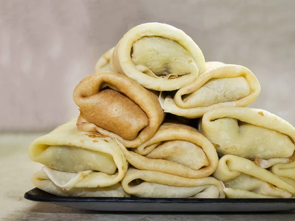 Mutfak masasının üzerinde kare bir tabakta dizilmiş doldurulmuş krep.