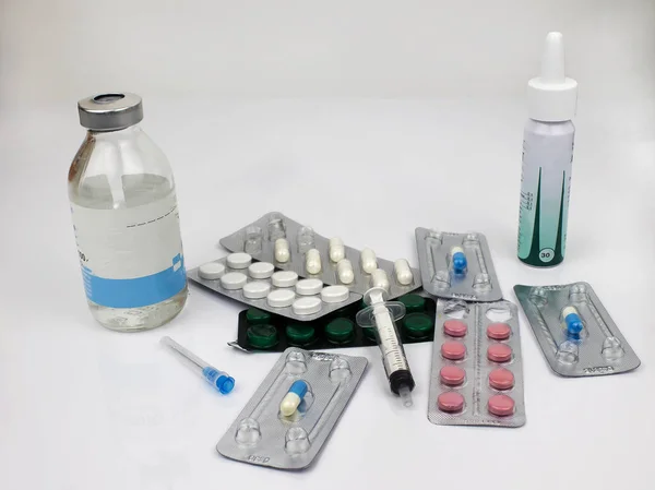 Tablets, capsules, solution bottle, nasal spray, syringe, needle for injection. Medicines are located on a white background.