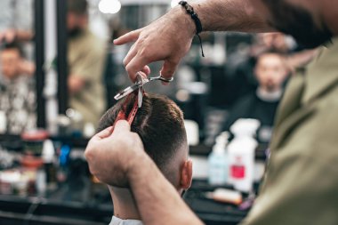 Kendine güvenen adam güzellik salonunda oturuyor. Erkek saç kesimi. Yumuşak odak.