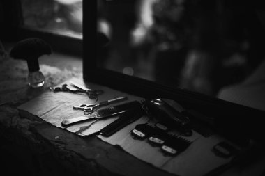 Aynanın önünde masaüstünde bir Kuaför araçları. Siyah ve beyaz fotoğraf Kuaför araçları. Fotoğraf karanlık anahtar.