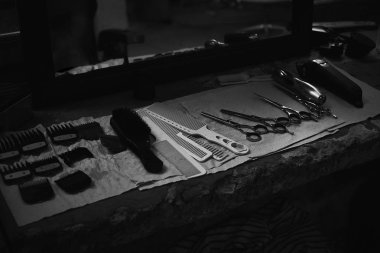 Aynanın önünde masaüstünde bir Kuaför araçları. Siyah ve beyaz fotoğraf Kuaför araçları. Fotoğraf karanlık anahtar.