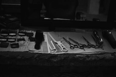 Aynanın önünde masaüstünde bir Kuaför araçları. Siyah ve beyaz fotoğraf Kuaför araçları. Fotoğraf karanlık anahtar.