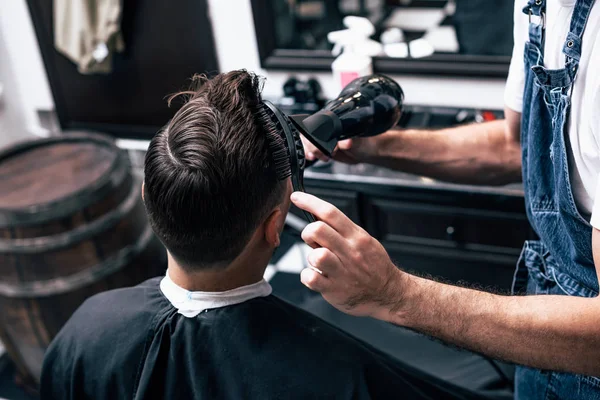 Peluquero en barbería cizalla pelo coche eléctrico a chico joven hipper para el peinado de moda . —  Fotos de Stock