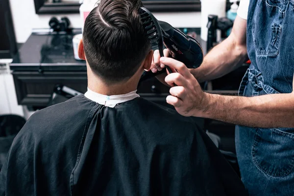 Um homem está num salão de beleza. Corte de cabelo e styling na barbearia. Homens cuidados com a barba e cabelo . — Fotografia de Stock