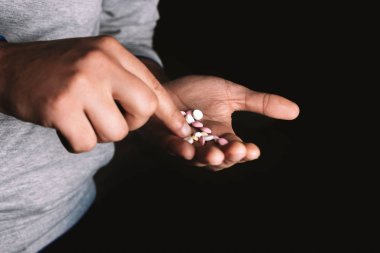 siyah arka plan üzerinde elinde haplar