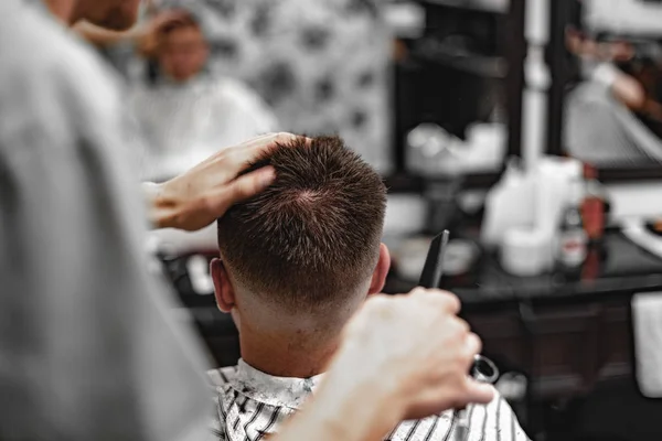 Corte de cabelo masculino numa barbearia. Cortes de cabeleireiro com tesoura . — Fotografia de Stock