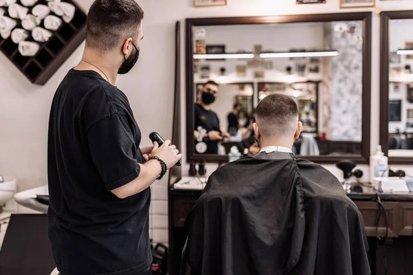 O trabalho final do barbeiro. O cliente olha para o corte de cabelo através do espelho . — Fotografia de Stock