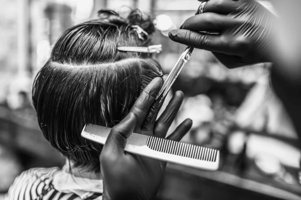 Barbeiro faz um corte de cabelo e estilo de cabelo em uma barbearia, salão de beleza. — Fotografia de Stock