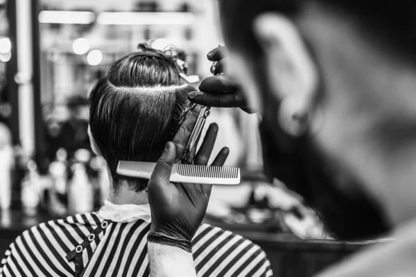 Barbiere fa un taglio di capelli e acconciatura in un barbiere, salone di bellezza. — Foto Stock