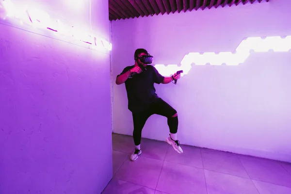 Manusia dengan helm realitas maya. Ruangan Neon dengan VR game. — Stok Foto