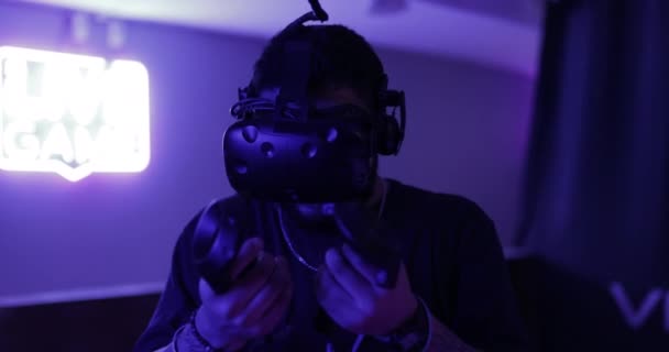 Un homme joue sur une console de jeu. Salle Neon VR. 