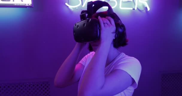 Chica lleva gafas VR en una habitación de neón. Una mujer se une a la realidad virtual . — Vídeos de Stock