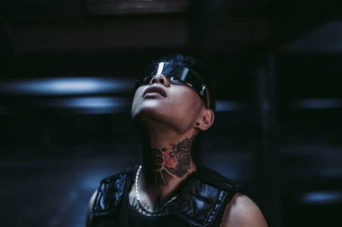 Siber punk tarzı. Bir şehirde dövmeli bir adam. Siber gözlük.