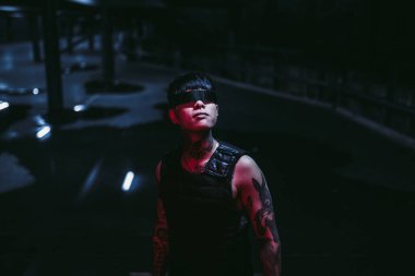 Siber gözlüklü bir adam gece şehrindeki ışığa bakıyor..