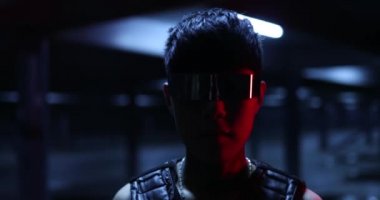 Karanlıktaki bir adam gözlüklerini çıkarır. Gece neon şehrinde siber punk.