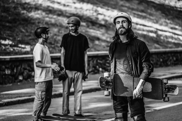 A group of guys ride longboards. Black and white portrait of a skateboarder. — Stock Photo, Image