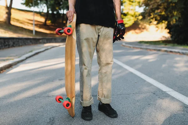El tipo sostiene una tabla con ruedas rojas. Skateboarding en la ciudad eterna. — Foto de Stock