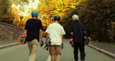 Arkadaş grubu gün batımında paten kayıyor. Çocuklar ellerinde patenlerle yürüyorlar..