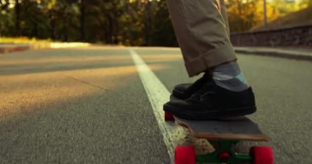 Парень прыгает на скейтборд и уходит на закат — стоковое видео