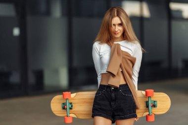 Kaykaylı güzel bir sarışının göğüs portresi. Şehirde yaşam tarzı.