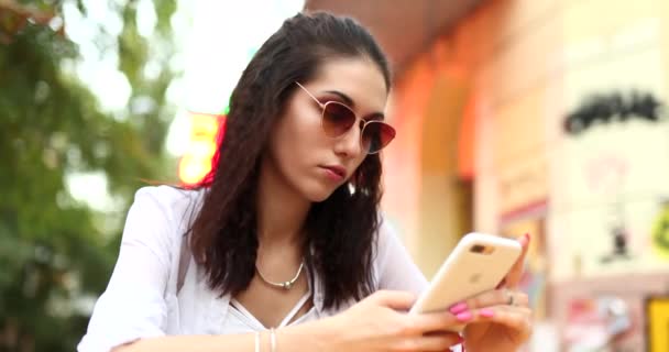 Mujer joven con gafas utiliza el teléfono. — Vídeos de Stock