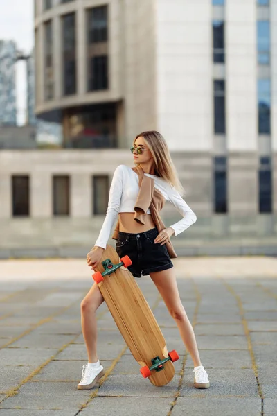 Junge Frau fährt mit Longboard durch die Stadt. — Stockfoto