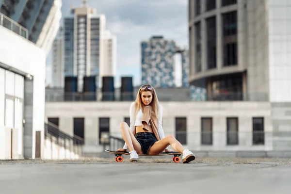 Junge Frau fährt mit Longboard durch die Stadt. — Stockfoto